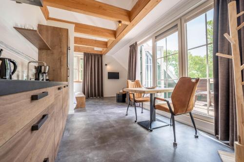 a kitchen with a table and chairs and windows at Appartementen De Witte Brugh in Buren