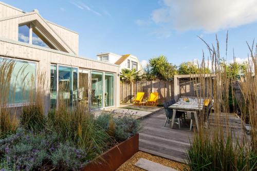 a patio with a table and chairs on a wooden deck at Insta-worthy 4br designer house 5 min to the beach in West Wittering