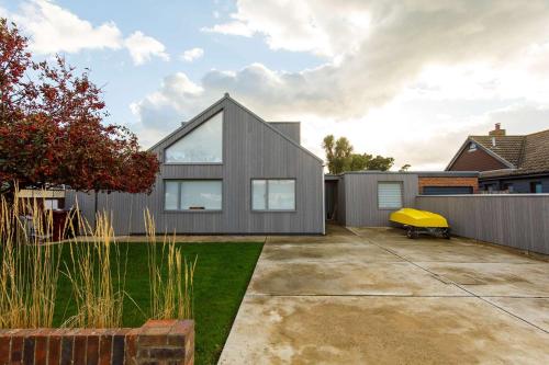 a gray house with a yellow object in a yard at Insta-worthy 4br designer house 5 min to the beach in West Wittering