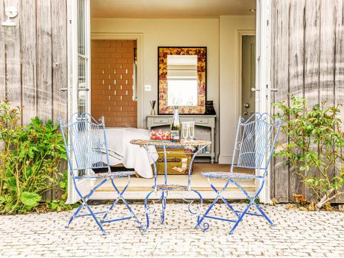 two blue chairs and a table on a patio at Spring House by The Suffolk Cottage Collection in Aldeburgh