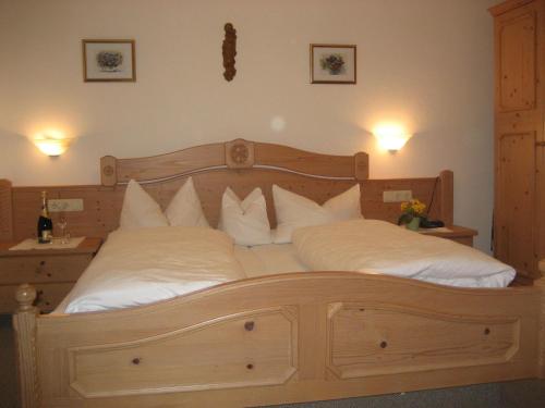 a bedroom with a large wooden bed with white pillows at Berghof Moar in Unterwössen