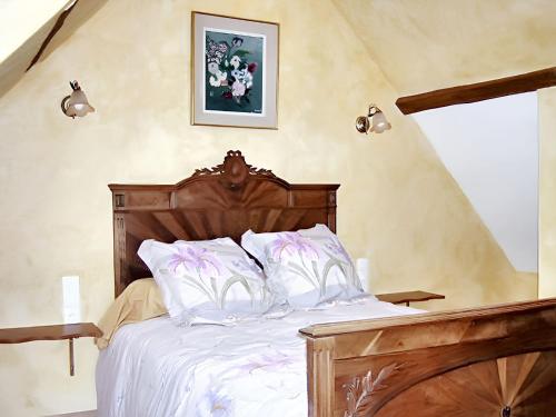 - une chambre avec un lit en bois et des oreillers blancs dans l'établissement Maison charmante à Chéronvilliers, à Chéronvilliers