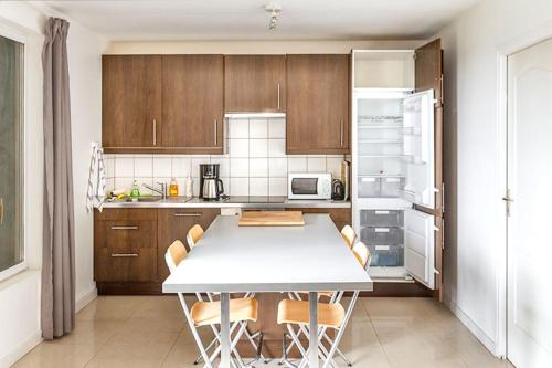 une cuisine avec une table avec des chaises et un réfrigérateur dans l'établissement Maison accueillante à Monthenault avec jardin privé, à Monthenault