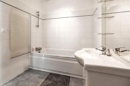 La salle de bains blanche est pourvue d'un lavabo et d'une baignoire. dans l'établissement Maison accueillante à Monthenault avec jardin privé, à Monthenault