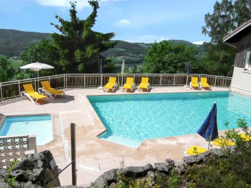 - une piscine avec des chaises longues jaunes dans l'établissement Chalet charmant au Tholy avec piscine partagée, à Le Tholy