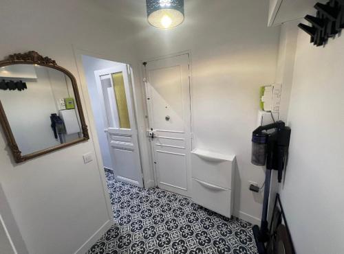 La salle de bains est pourvue d'une porte blanche et d'un miroir. dans l'établissement Très bel appartement proche Disney Paris, à Les Pavillons-sous-Bois