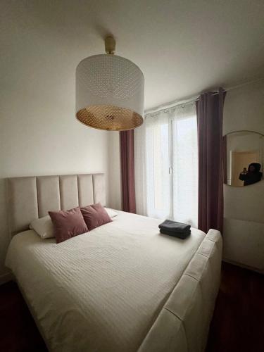 une chambre avec un grand lit blanc avec une grande fenêtre dans l'établissement Très bel appartement proche Disney Paris, à Les Pavillons-sous-Bois