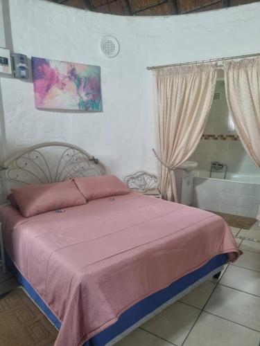 a bedroom with a bed with pink sheets and a tub at Hibberdene Cottage Crew in Hibberdene