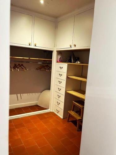 Elle comprend un dressing avec des armoires blanches et un sol orange. dans l'établissement La maison bleue, à Bouzigues