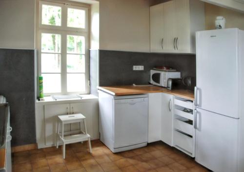 Il comprend une cuisine équipée d'appareils électroménagers blancs et d'un réfrigérateur blanc. dans l'établissement Maison charmante Jugon-les-Lacs, à Jugon Les Lacs