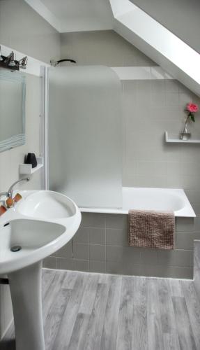 La salle de bains blanche est pourvue d'un lavabo et d'une baignoire. dans l'établissement Maison charmante Jugon-les-Lacs, à Jugon Les Lacs