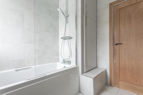 a bathroom with a shower and a bathtub and a door at The little cottage in Queensbury