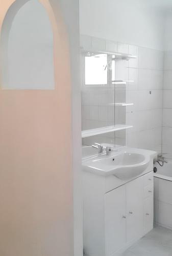 une salle de bain blanche avec un lavabo et un miroir dans l'établissement Maison charmante avec piscine privée à Orthoux-Sérignac-Quilhan, à Bragassargues