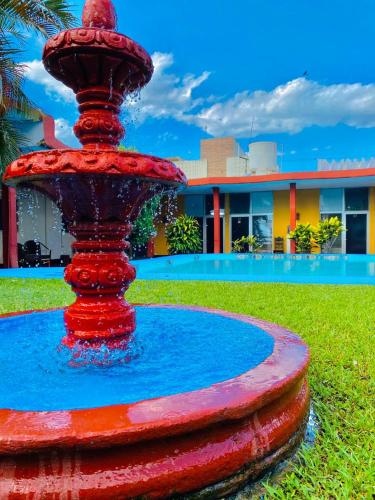 a red fountain in front of a building at Hotel Del Valle in El Naranjo