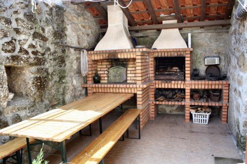 une cuisine extérieure avec une table en bois et une cheminée dans l'établissement Spacious Family House in Nogueira with Garden, à Moita