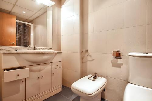 a white bathroom with a sink and a toilet at Comfortable apartment in Platja de la Pineda 70 m² with pool in La Pineda