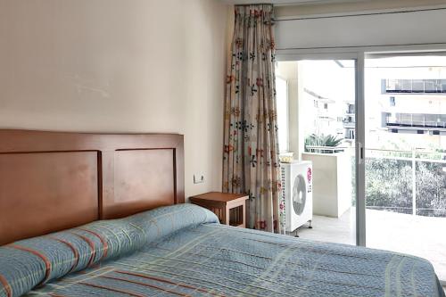a bedroom with a bed and a sliding glass door at Comfortable apartment in Platja de la Pineda 70 m² with pool in La Pineda