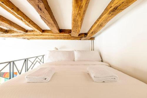 - une chambre avec un lit doté de draps blancs et de plafonds en bois dans l'établissement Stylish Parisian Flat in the Marais - SAINT-PAUL, à Paris