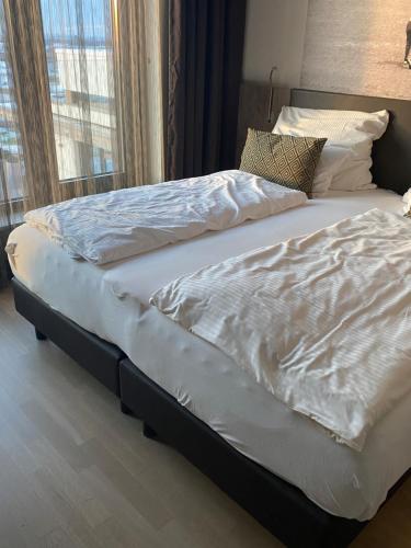 a large bed with white sheets and pillows on it at Hotel TheGreen in Cologne