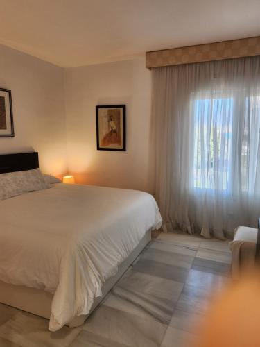 a bedroom with a white bed and a window at LAALCAZABA Garden in Marbella