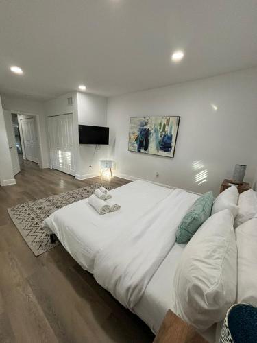 a bedroom with a large white bed with a flat screen tv at Cozy 1 Bedroom Duplex in Central Tampa in Tampa