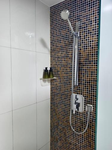 a shower in a bathroom with a tiled wall at South China Sea Place by Kinabina Homestay in Kota Kinabalu