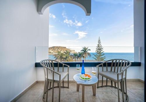 a table and two chairs in a balcony with a view of the ocean at H10 Costa Mogán - Adults Only in Playa del Cura