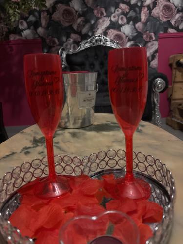 two red wine glasses sitting on top of a table at Romantisme et glamour 2 avec spa , clim et jardin in Dijon