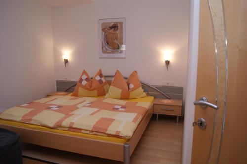 フルプメスにあるHaus Erikaのベッドルーム1室(オレンジと黄色の枕が付いたベッド1台付)