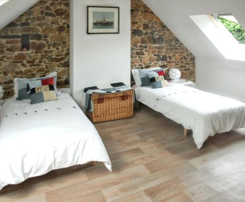two beds in a room with a stone wall at Maison charmante à Pordic, cheminées et jardin clos in Pordic