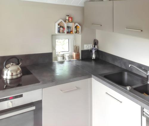 a kitchen with white cabinets and a sink at Maison charmante à Pordic, cheminées et jardin clos in Pordic