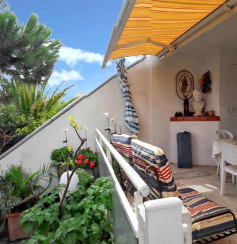 une terrasse avec un canapé, des plantes et un parasol dans l'établissement Maison familiale à Sainte-Marie, à Sainte-Marie-Plage
