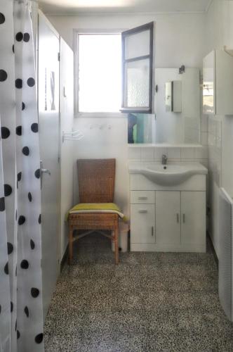 La salle de bains est pourvue d'une chaise, d'un lavabo et d'une fenêtre. dans l'établissement Maison accueillante à Orgnac-l'Aven avec piscine partagée, à Orgnac-lʼAven