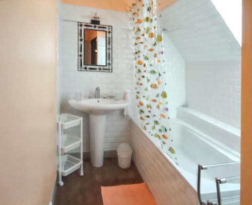 a white bathroom with a sink and a bath tub at Charmante maison avec cheminée à Saint-Jacut-de-la-Mer in Saint-Jacut-de-la-Mer