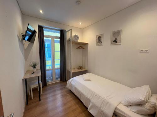 a white bedroom with a bed and a window at Bairro Alto Hostel in Lisbon