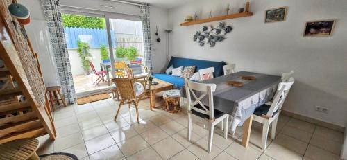 a living room with a table and chairs and a couch at Maison charmante à Vaux-sur-Mer avec piscine partagée in Vaux-sur-Mer
