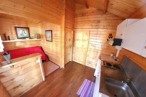 an inside view of a wooden cabin with a red couch at Bungalow charmant à Vincendo, St-Joseph avec piscine partagée in Saint-Joseph