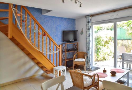 a living room with a staircase and a table and chairs at Maison charmante à Vaux-sur-Mer avec piscine partagée in Vaux-sur-Mer