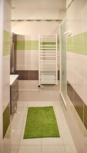 La salle de bains est pourvue d'une douche et d'un tapis vert. dans l'établissement Maison charmante à Vaux-sur-Mer avec piscine partagée, à Vaux-sur-Mer