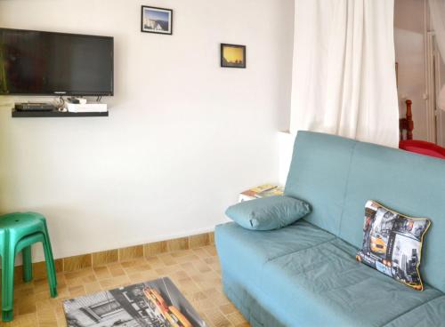 a living room with a blue couch and a television at Studio cocooning à Saint Anne / 27 m² / jardin fleuri in Sainte-Anne