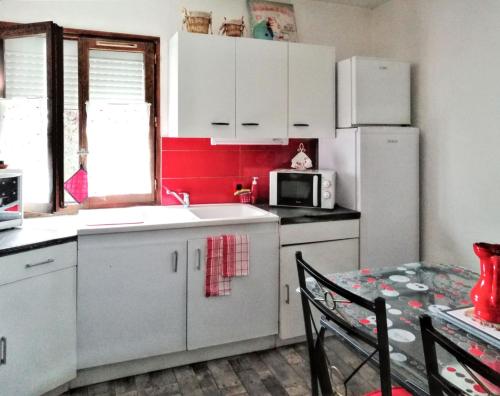 a kitchen with white cabinets and a white refrigerator at Appartement charmant à Villeneuve avec jardin in Villeneuve-dʼAveyron