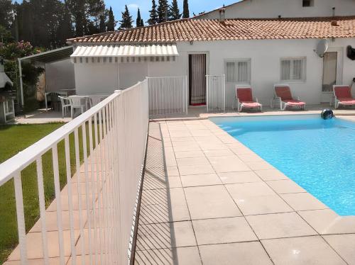 une piscine à côté d'une clôture blanche et d'une maison dans l'établissement Villa charmante à Meynes avec piscine privée, à Meynes