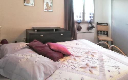 a bed with pillows on it in a bedroom at Appartement charmant à Villeneuve avec jardin in Villeneuve-dʼAveyron