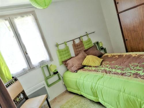 a bedroom with a green bed and a window at Appartement charmant à Villeneuve avec jardin in Villeneuve-dʼAveyron