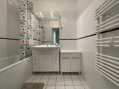 Un baño blanco con lavabo y espejo. en Duplex villa 2, en Pau
