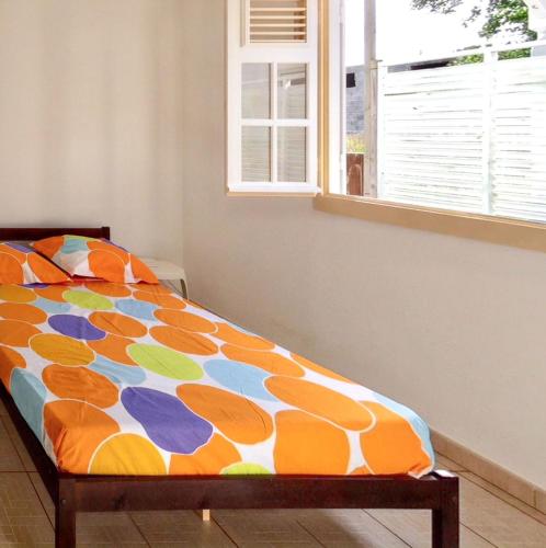 a bed in a bedroom with a colorful comforter at Maison accueillante à Anse-Bertrand avec jardin privé 70 m² in Anse-Bertrand