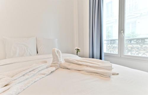 - un lit blanc avec des draps blancs et une fenêtre dans l'établissement Apartment near Mairie Paris 10ème - III, à Paris