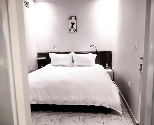 a bedroom with a bed with white sheets and pillows at Lux Inn App in Kigali