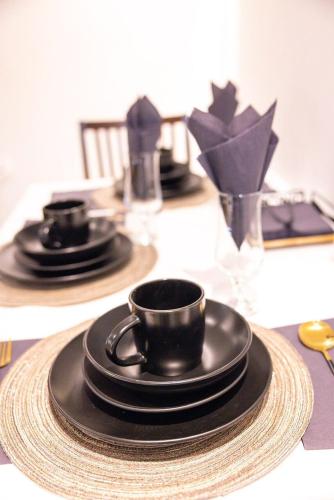 a table with black cups and plates on a table at Lux Inn App in Kigali