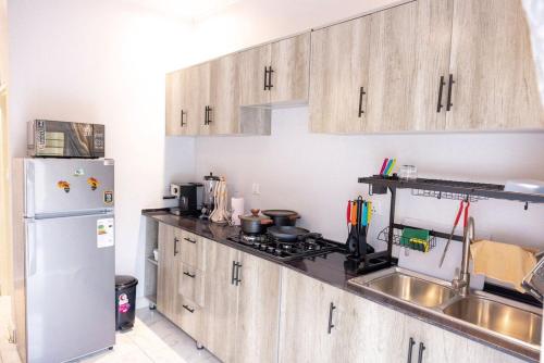 a kitchen with wooden cabinets and a white refrigerator at Lux Inn App in Kigali